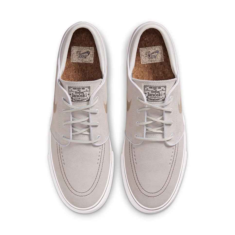Light gray low-top sneakers with white laces, stitched panels, and tan interior lining